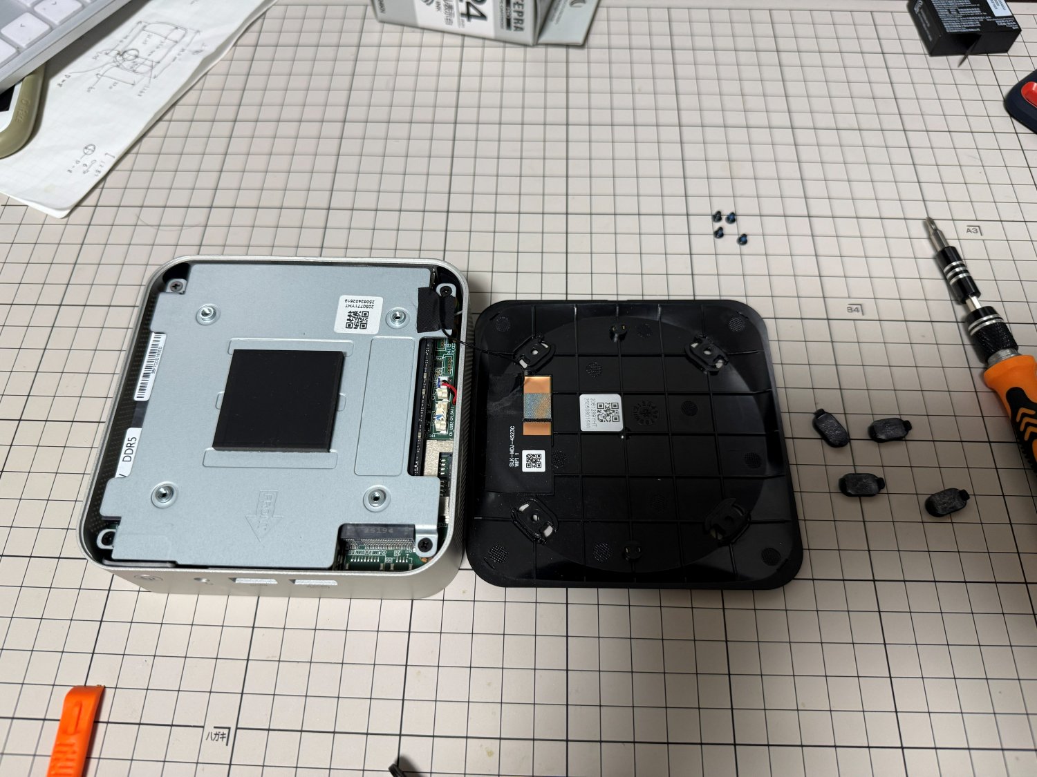 GEEKOM A8の底面カバーを開けた状態。金属シールドと、外したゴム足4個が並んでいる