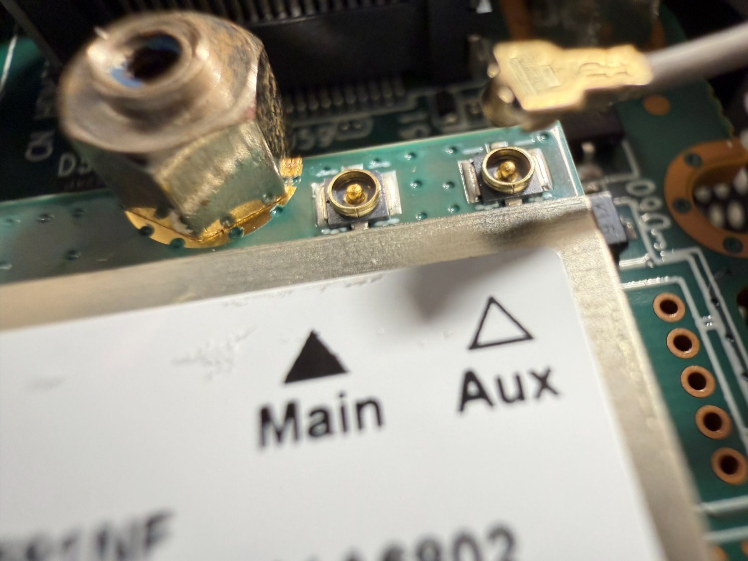 Wi-Fiカード上のMHF4コネクタ（基板側）2個のマクロ写真。MainとAuxの刻印が見える