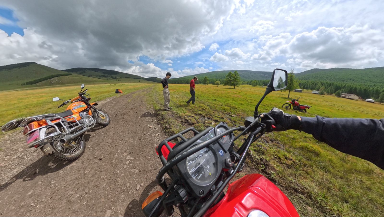 草原の轍の脇に停まったバイクと、様子を見に来てくれた地元の人